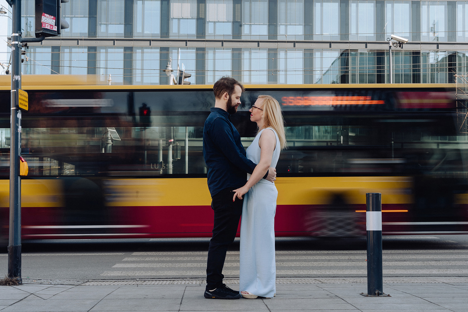 Nat and Alex standing together in front of a passing bus