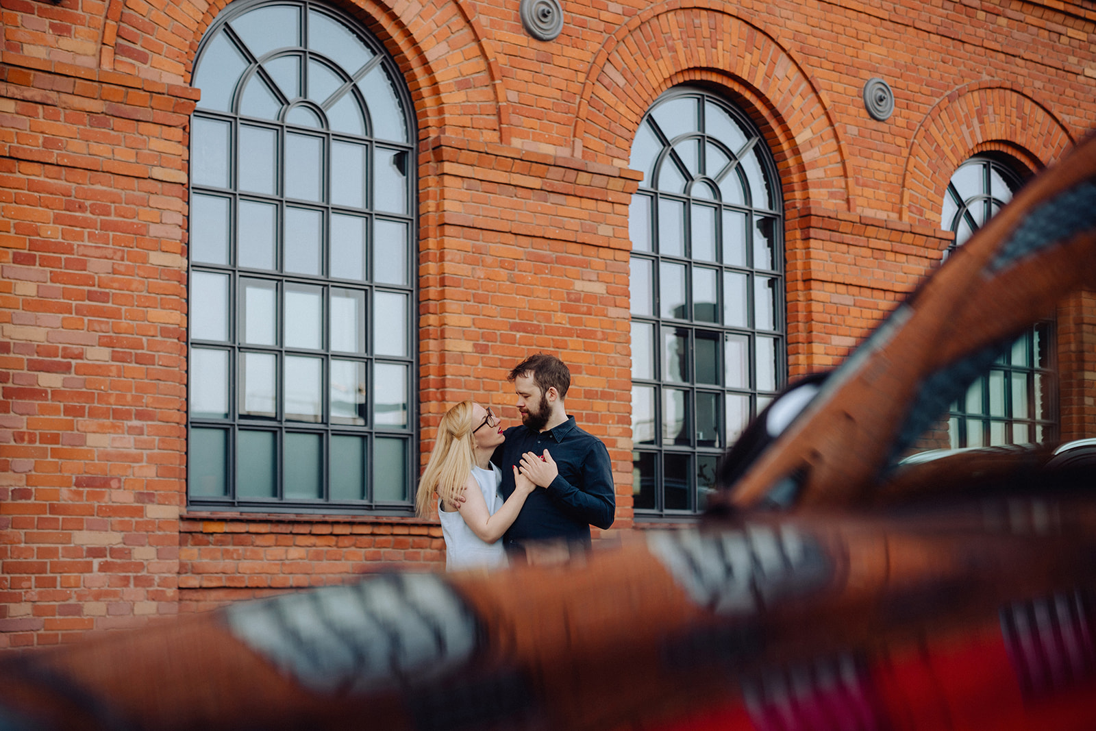 Nat and Alex embracing in front of brick building